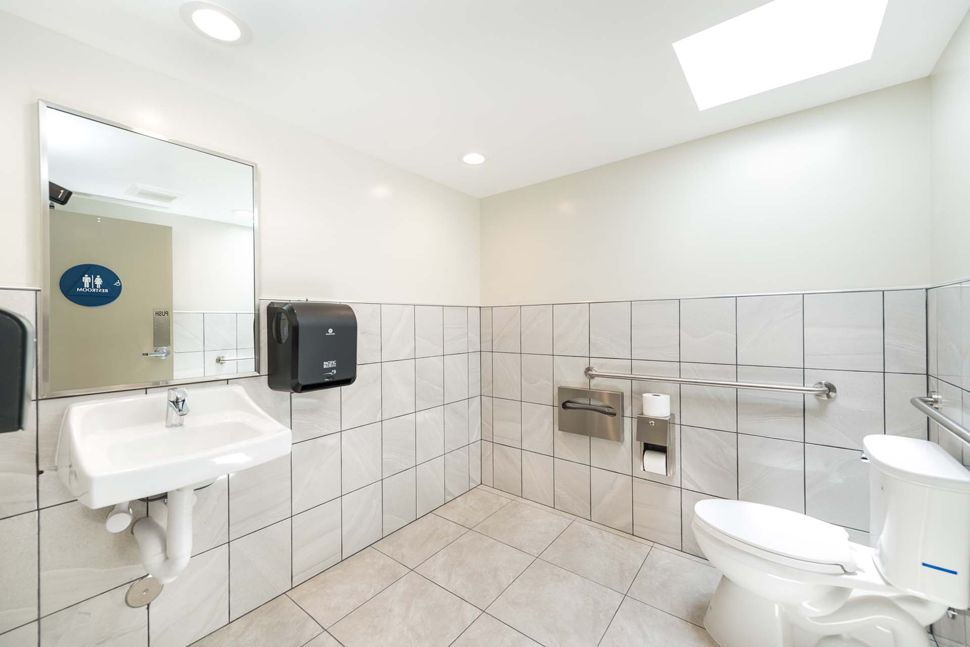 Inside large apartment complex bathroom with tan tiles.